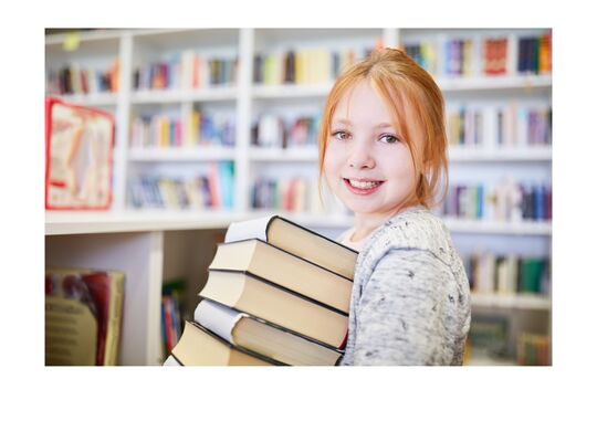 Petite fille qui tient des livres dans ses bras